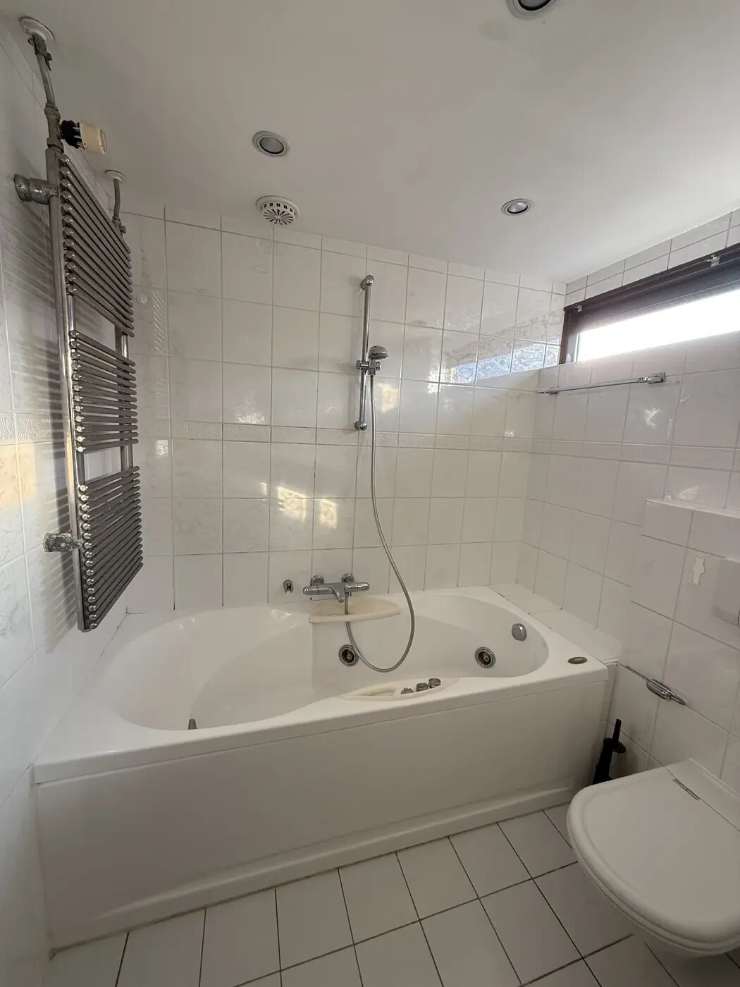 Badkamer voor de renovatie, met hoekbad en witte wandtegels